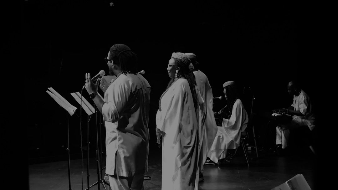 Ensemble on stage in black and white
