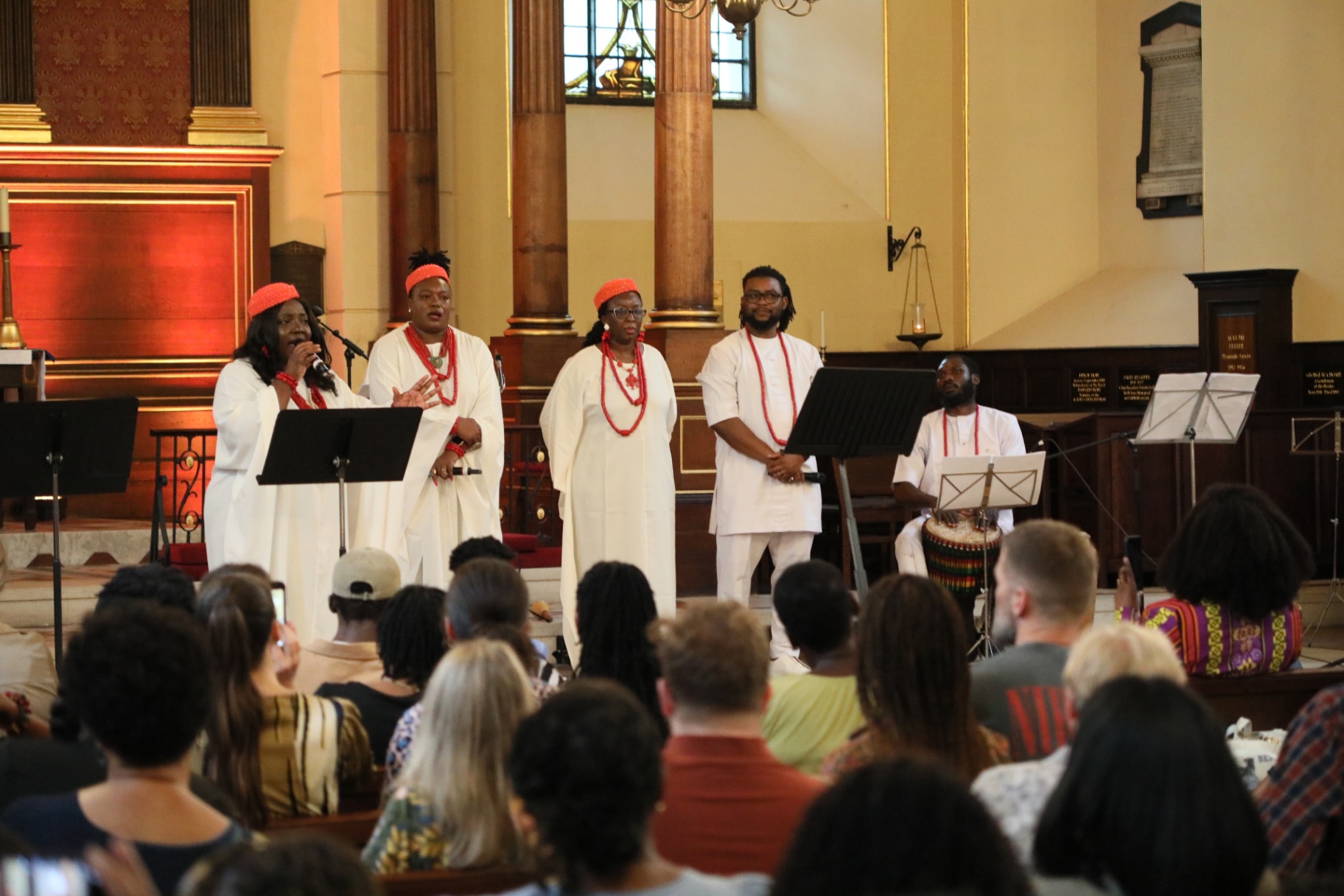 Ensemble in white robes and coral regalia performing