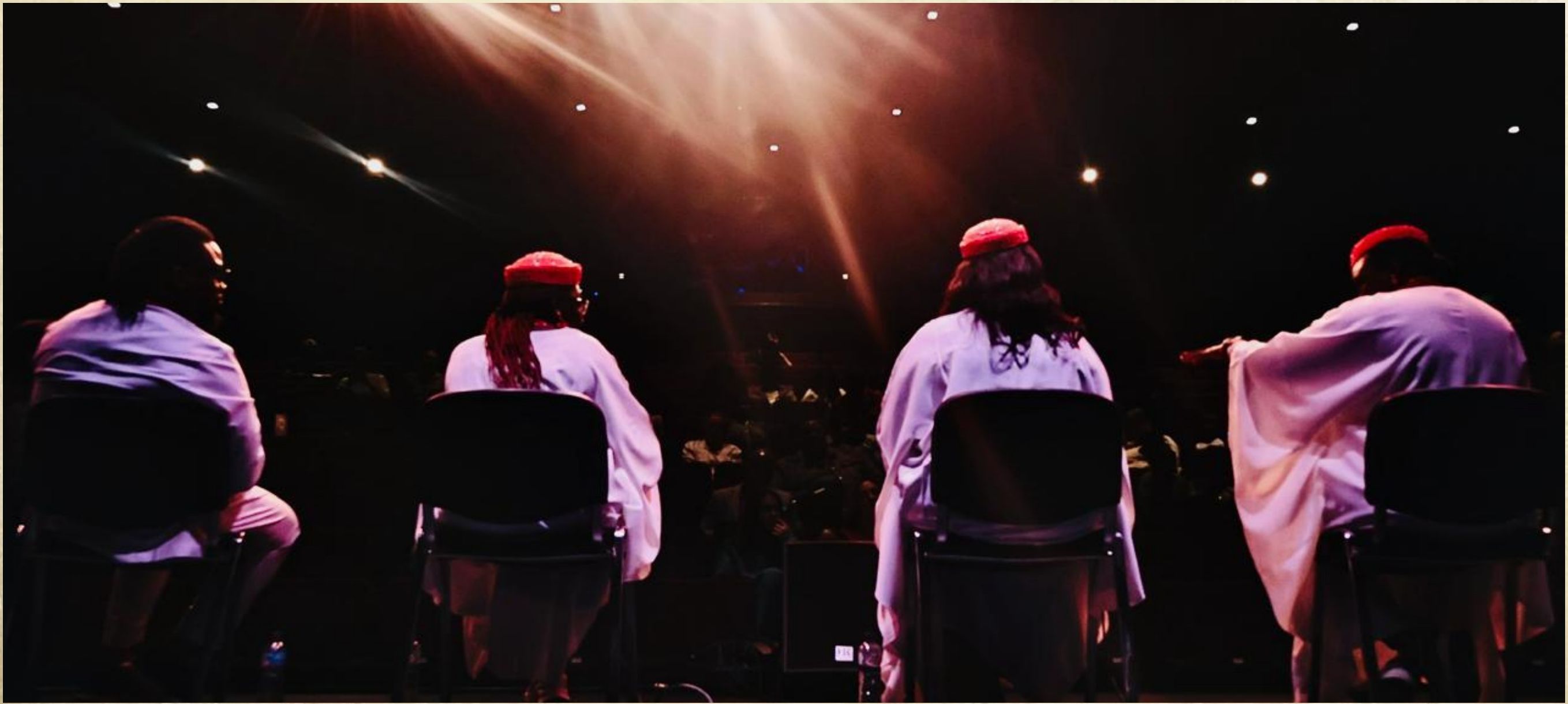 Four performers on stage at the R&D sharing in Peterborough, backs turned to the camera